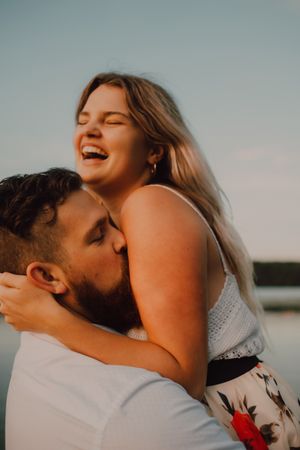 Loving man carrying happy woman on hands on shore