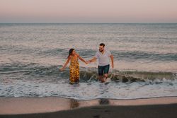 Lovely couple running holding hands on sandy beach
