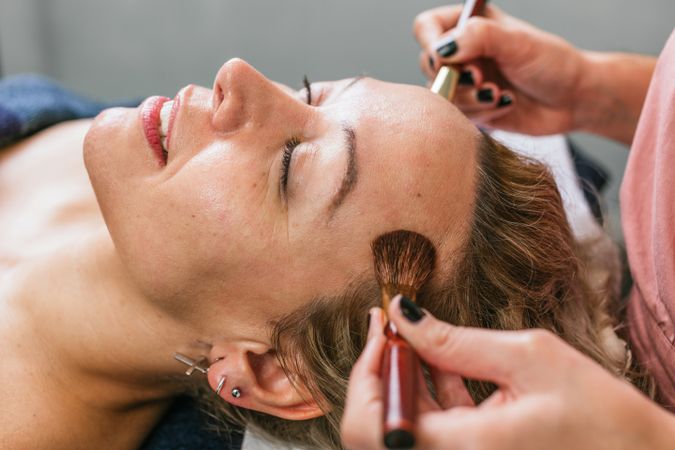 Crop visagiste doing makeup for woman in beauty salon