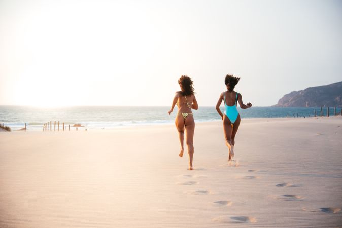 unrecognizable women enjoying on beach in swimsuit