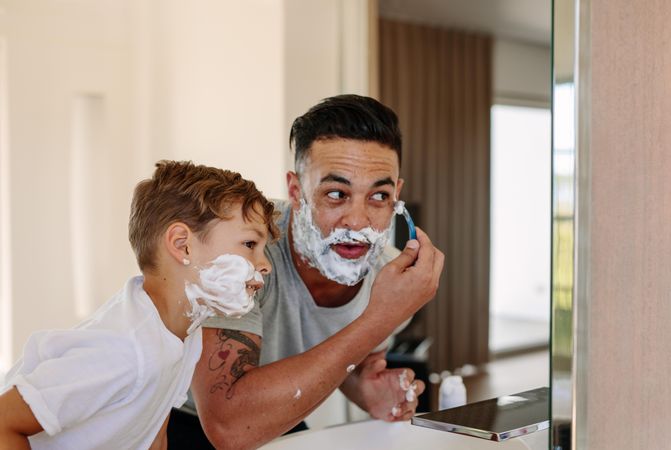 Father and son shaving together at home bathroom