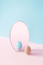 Egg and mirror on pastel pink and blue background