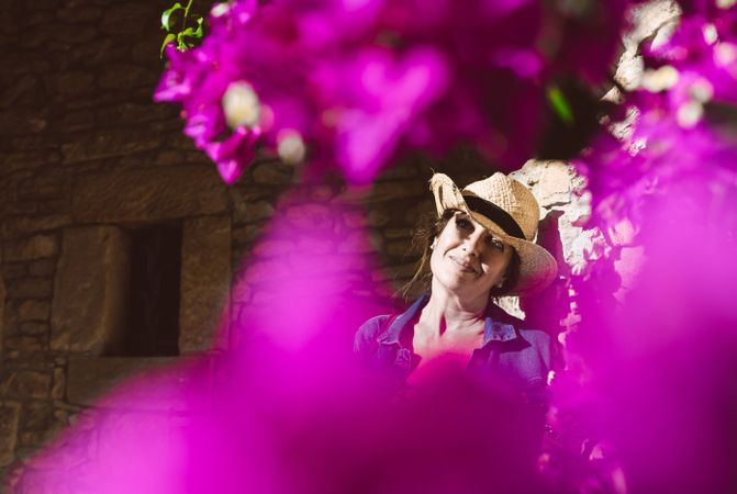 Woman standing near a wall with flower shrubs
