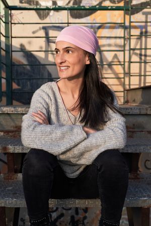 Smiling female in pink scarf sitting on grunge stairs