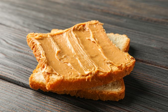 Peanut butter sandwich on wooden background, space for text and closeup