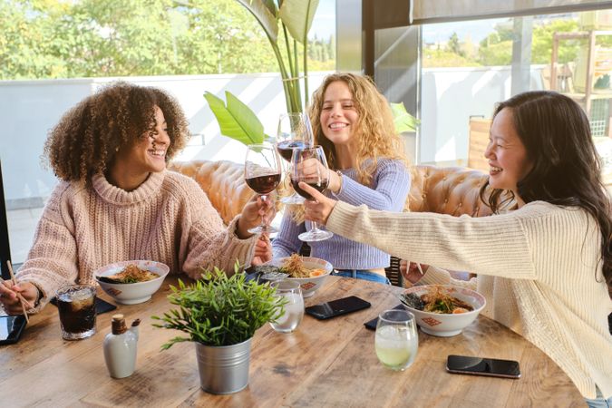 Cheerful diverse women drinking wine in cafe