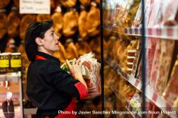 Woman in butcher shop arranging meat on shelf 42w73b