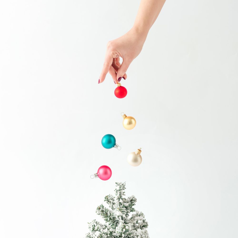 Hand sprinkling baubles on tree
