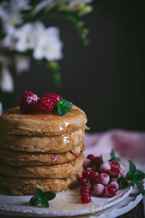 Pile of raspberry pancakes with honey on plate