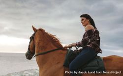 Woman horse riding along the sea shore in evening 42LM70