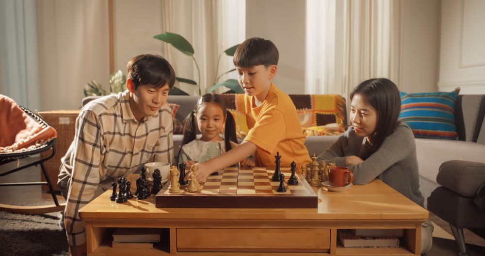Family Chess Tournament at Home. Father, Mother, Daughter and Son Playing Intellectual Chess Game together.
