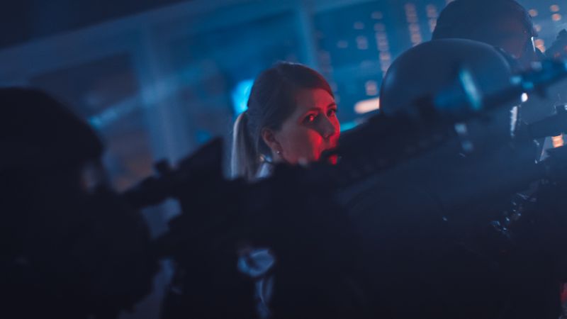 Masked Squad of Armed SWAT Police Officers Rescue a Female Hostage in a Dark Seized Office Building with Desks and Computers.