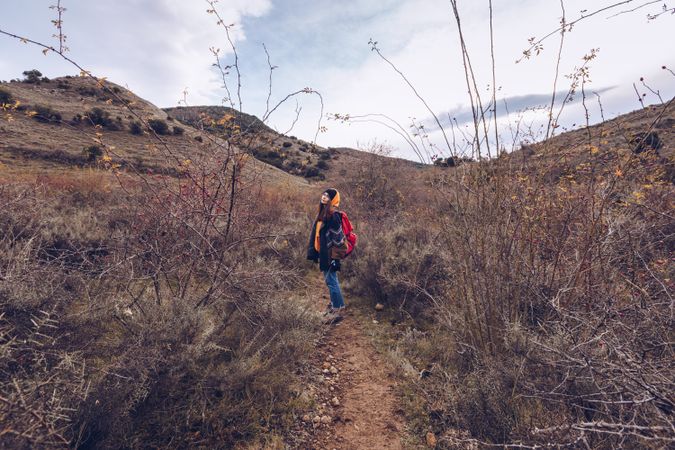 Hiker with backpack walking along pathway in autumn forest