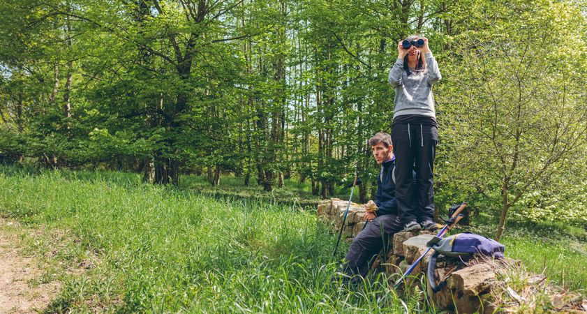 Couple doing trekking looking with binoculars