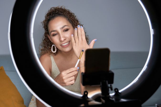 Visagiste woman demonstrating professional brush for makeup whil
