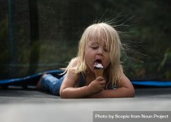 Young girl sitting on the ground eating ice cream 4BxDd0