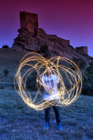 Man with burning sparklers in landscape