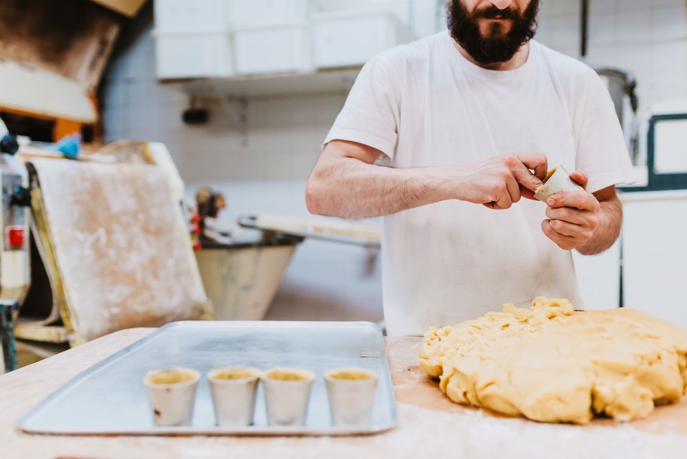 Bearded confectioner putting dough into cup