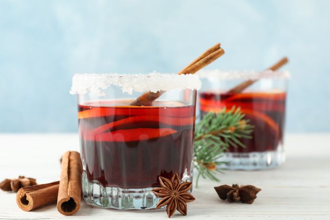 Glasses of tasty mulled wine on blue wooden background, space for text
