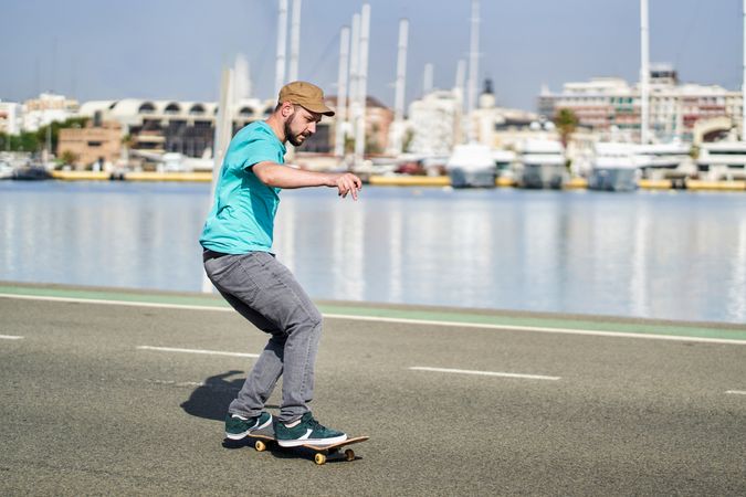 a young boy riding a skateboard on a road next to the harbor