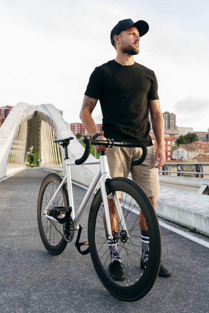 Cheerful man with bicycle standing on footbridge