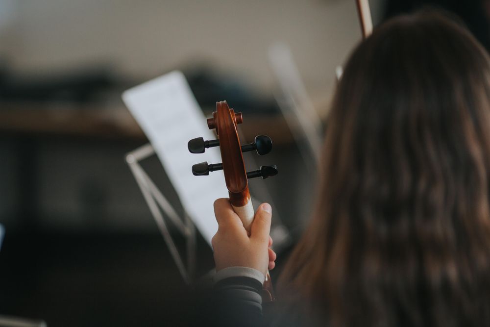Student studying sheet music with focus on instrument