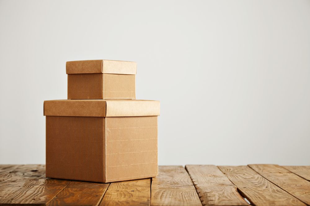 Two cardboard boxes stacked on wooden table