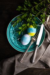 Spring table setting with branch on teal patterned plate and decorative eggs