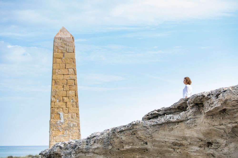 Young woman near brick monument and blue sky