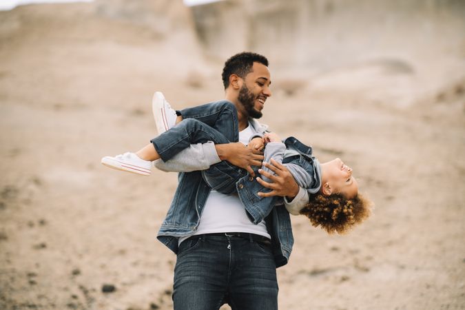 Black father playing with child on ground
