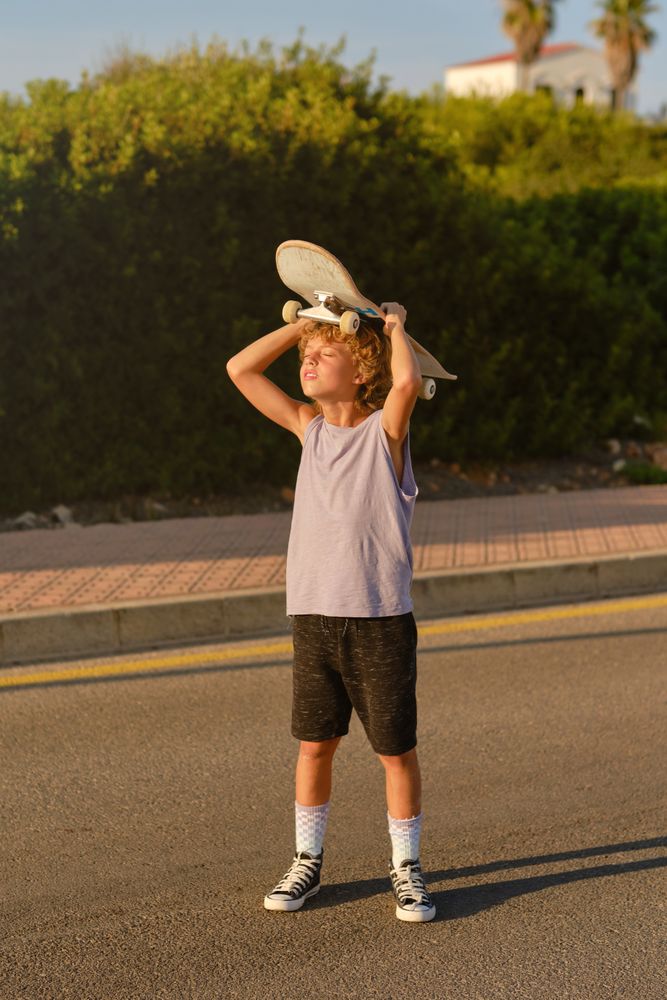 Boy standing with skateboard on road