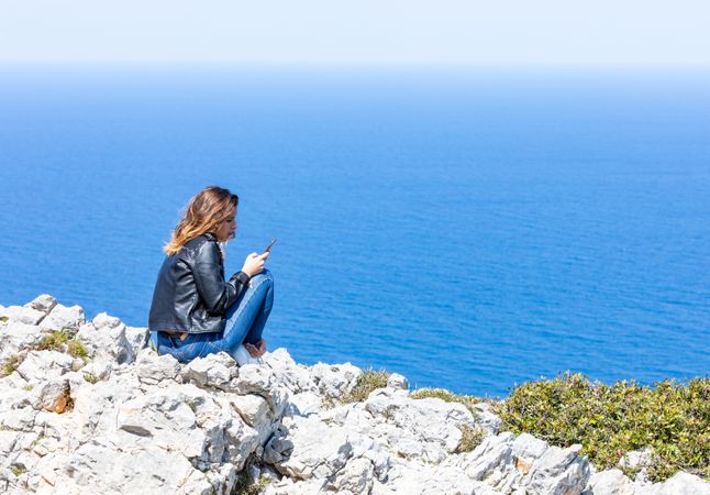 Young female using smartphone near sea