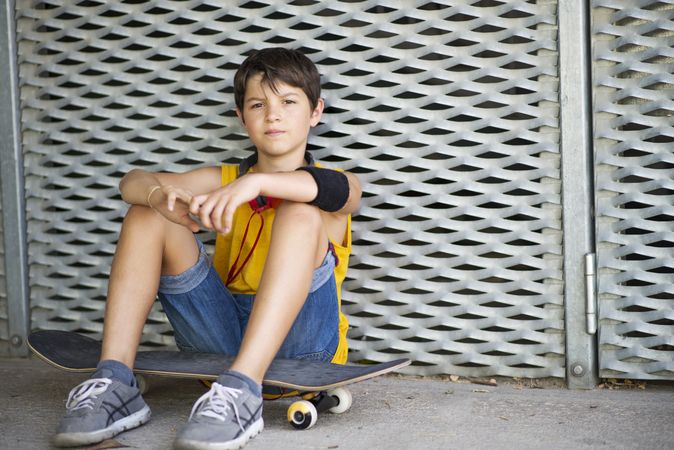 Casual dressed young serious teen skater outdoors
