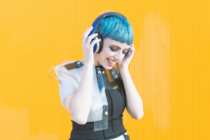 Cool informal woman in headphones on yellow wall