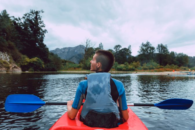 Female kayaking with paddle in raised hands