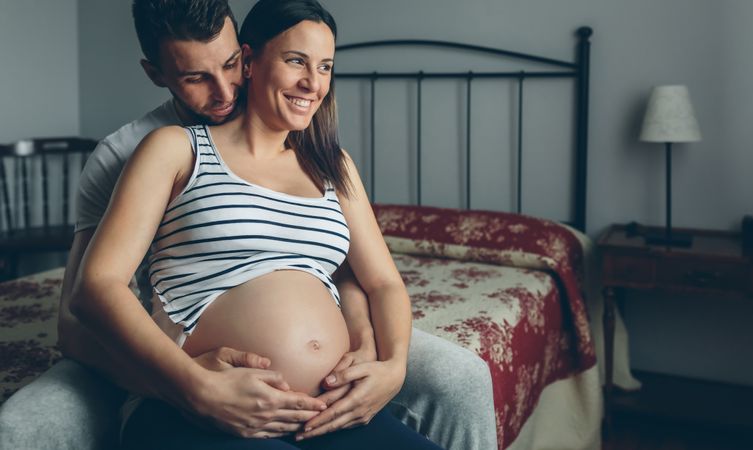 Pregnant woman embraced by her husband