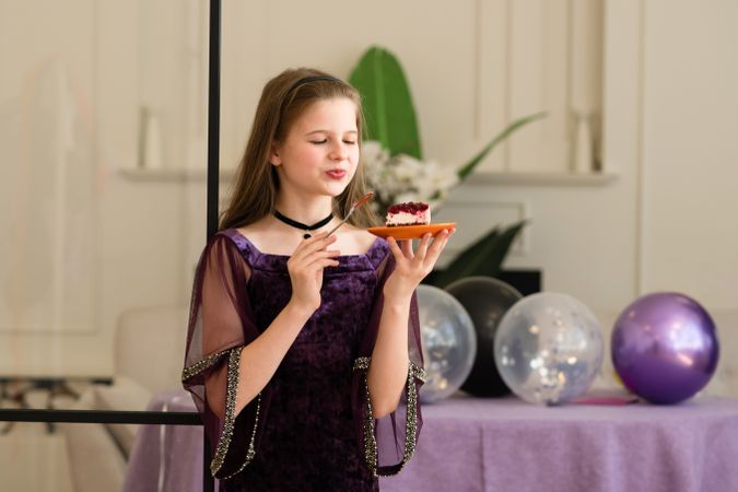 Girl enjoying slice of cake at birthday party.