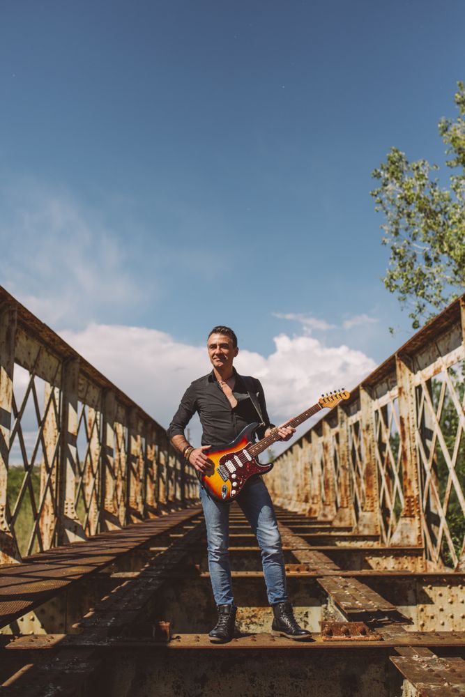Man with guitar standing on bridge
