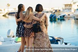Rear view of three women in summer dresses looking out from pier 0gknl0