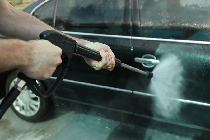 A man washes a car in a manual car wash. Clear car