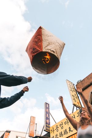 Cropped image of people lighting up a paper lantern outdoor in Taiwan