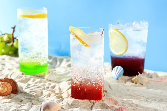 Three Glass of Various Lemonade Summer Drink on Beach Sand Setting