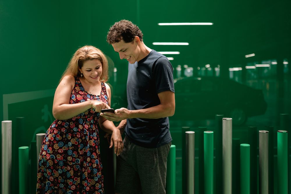 Couple browsing smartphone on green parking lot