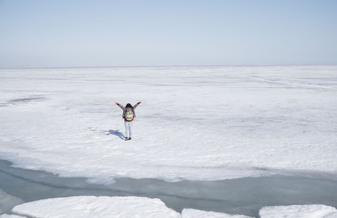 Young adult woman outdoors travelling with backpack in icy lands