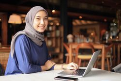 Asian Indonesian Muslim Businesswoman Wearing Hijab Working  with Laptop
