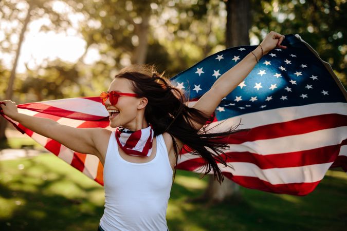 Young woman enjoying in park holding USA flag