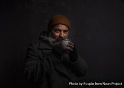Homeless smiling middle-aged man with a gray beard holding a cup of hot tea 5pKnO0
