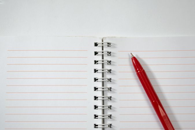 Open notebook and red pen isolated on blank background