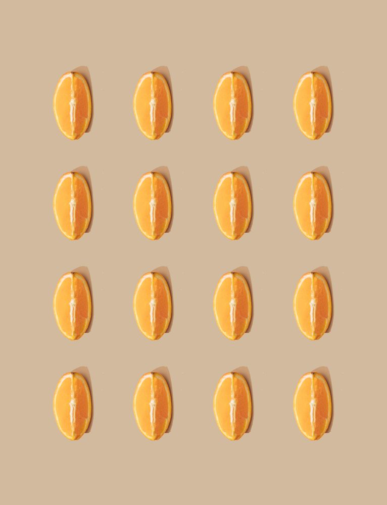 Pattern of orange fruit slices and pastel sand background