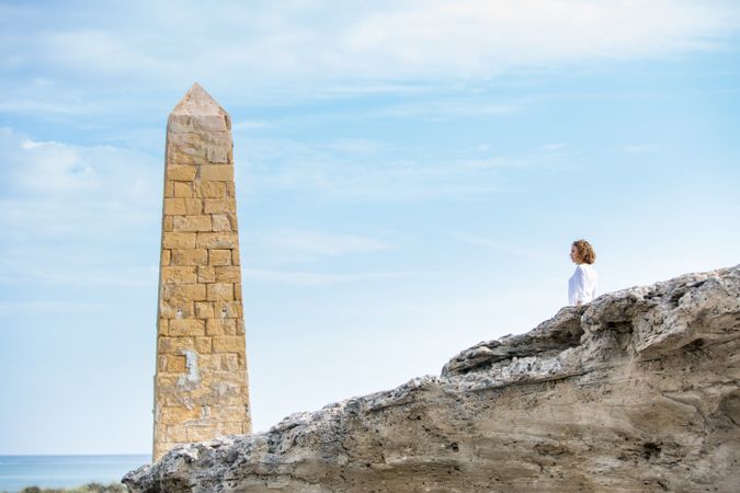 Young woman near brick monument and blue sky